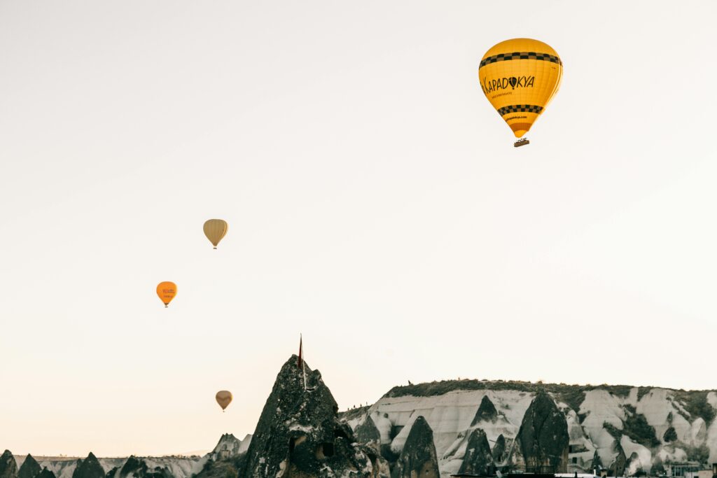 Hot air balloons float over the unique rock formations of Cappadocia, Turkey at sunrise.