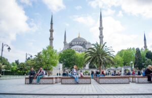 Daytime view of the Blue Mosque in Istanbul with people relaxing in the foreground. A blend of history and daily life.