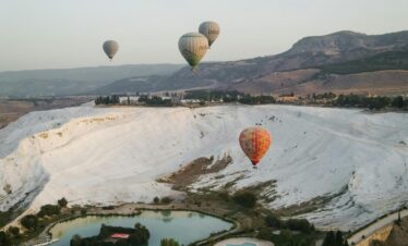 Scenic view of hot air balloons floating over Pamukkale travertines in Türkiye.