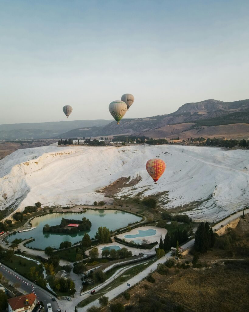 Scenic view of hot air balloons floating over Pamukkale travertines in Türkiye.