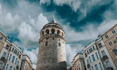 Captivating view of Galata Tower surrounded by historic architecture and dramatic clouds in Istanbul, Turkey.