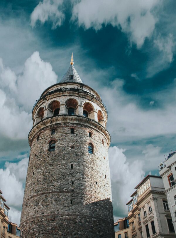 Captivating view of Galata Tower surrounded by historic architecture and dramatic clouds in Istanbul, Turkey.