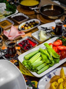 Vibrant Turkish breakfast with fresh vegetables, cheeses, and tea served in a cozy setting.