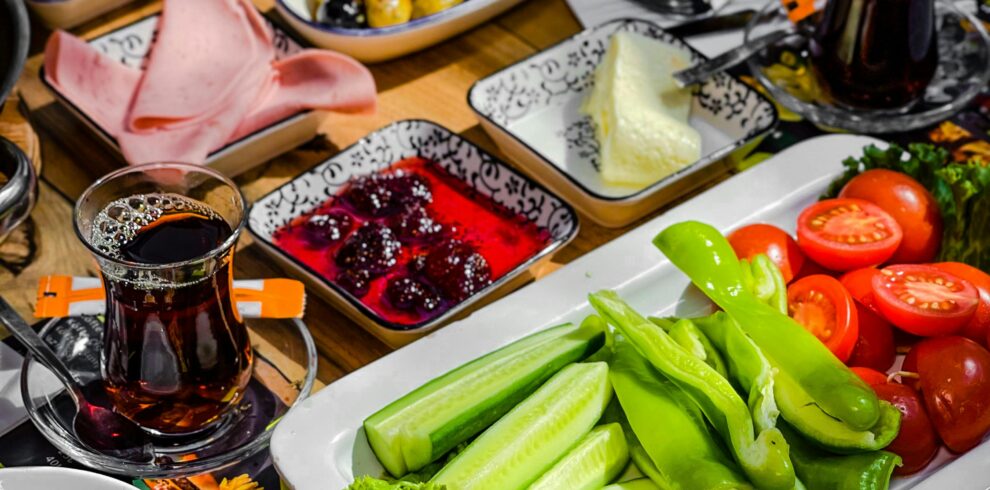 Vibrant Turkish breakfast with fresh vegetables, cheeses, and tea served in a cozy setting.